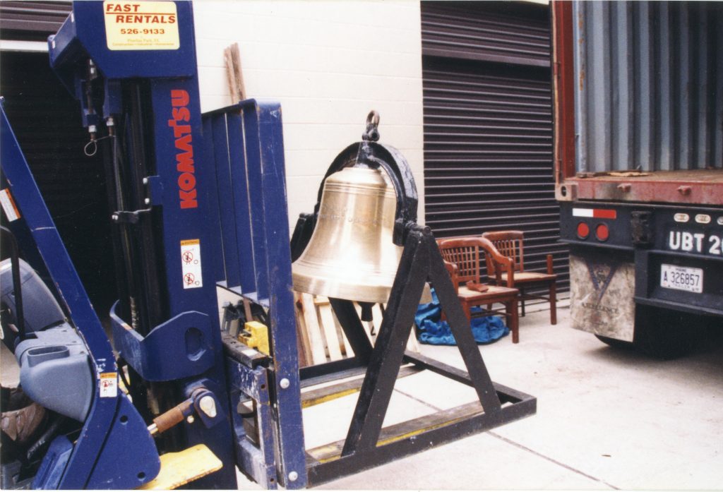A brass bell being moved on a forklift