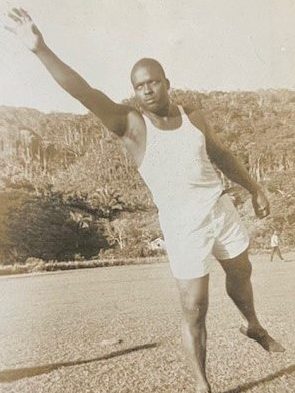 Full body portrait of Joseph French in sportswear-like attire and preparing to catch something.