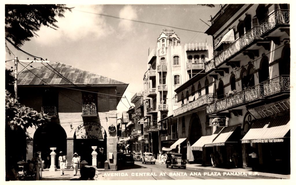 Black and white photo of cars and people walking along a street in Panama City, Panama.