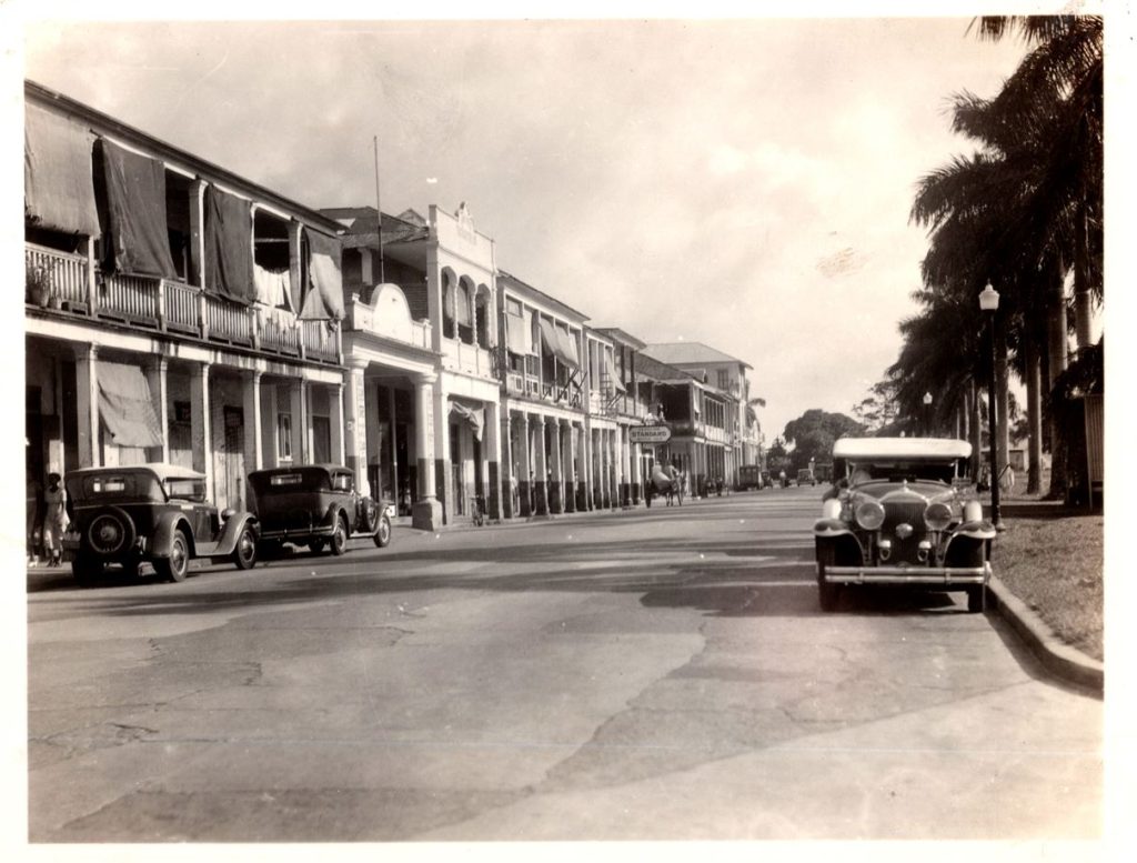 Black and white photo of cars left-hand driving on the road in Colon